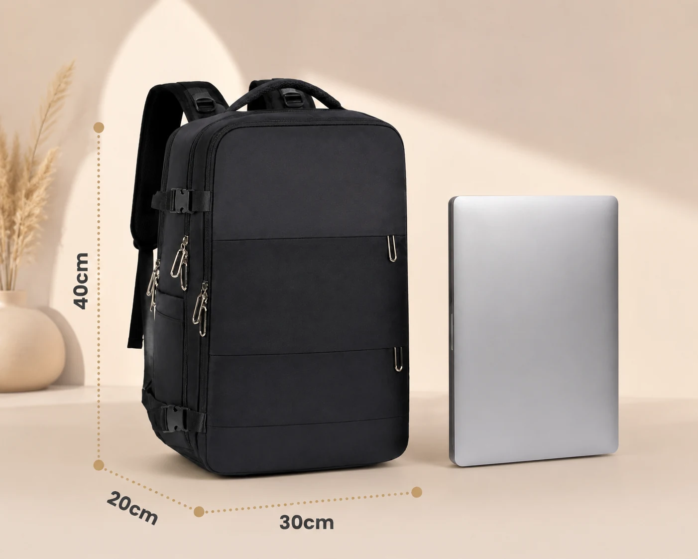Czarny plecak obok srebrnego laptopa, z widocznymi wymiarami: 40 cm wysokości, 30 cm szerokości i 20 cm głębokości.