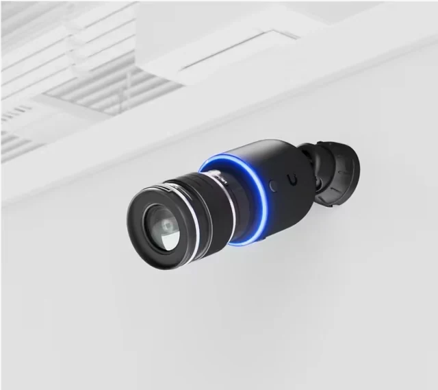 Black camera with a large lens and blue light ring, mounted on a ceiling bracket