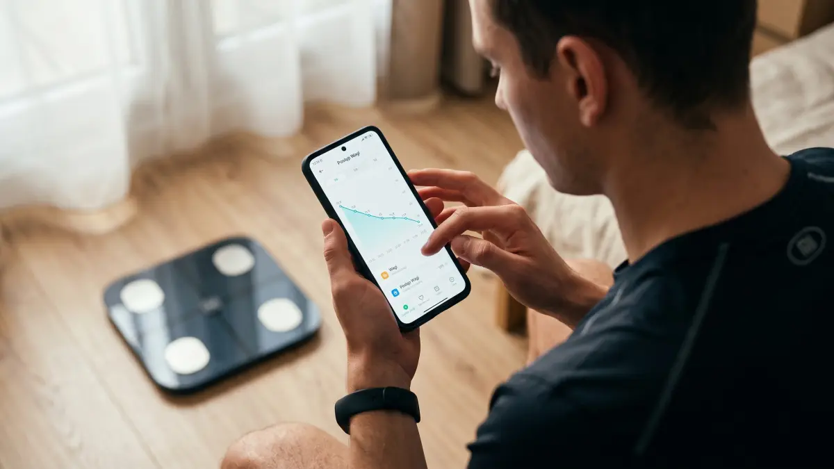 Osoba przeglądająca wykres na telefonie, z czarną wagą Xiaomi w tle.