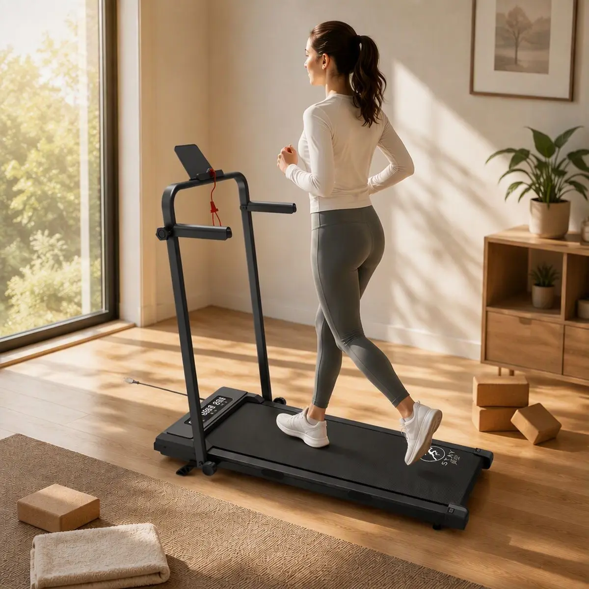 Kobieta ćwiczy na bieżni domowej StayFit Aurora z poręczą w jasnym wnętrzu podczas treningu