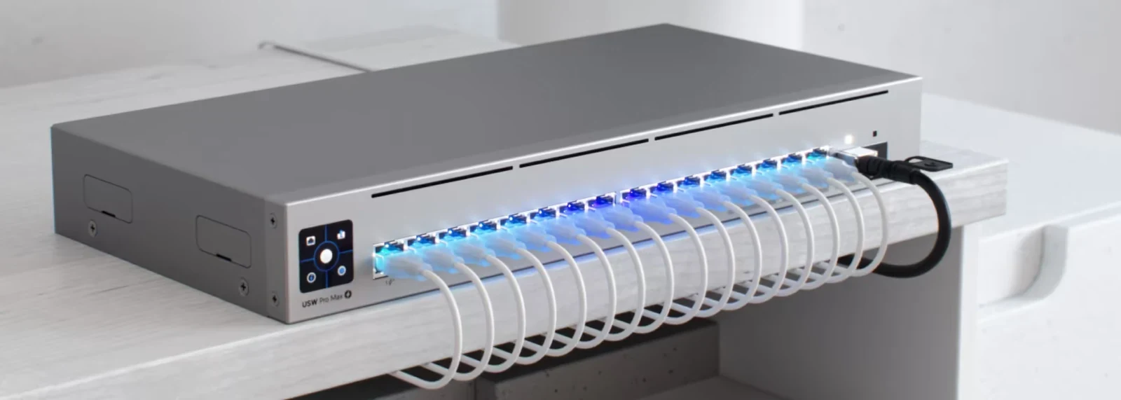 Ön panelinde çok sayıda Ethernet kablosu bağlı ve bağlantı noktaları aydınlatılmış gri switch