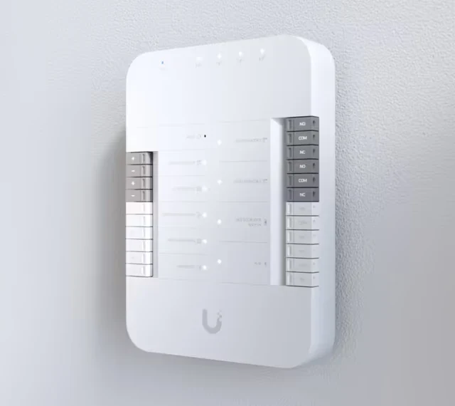 Módulo rectangular blanco en la pared con una serie de terminales a los lados y LED en la parte frontal
